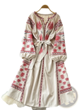 A cream-colored embroidered boho midi dress with intricate red embroidery and a tied waistband in beige
