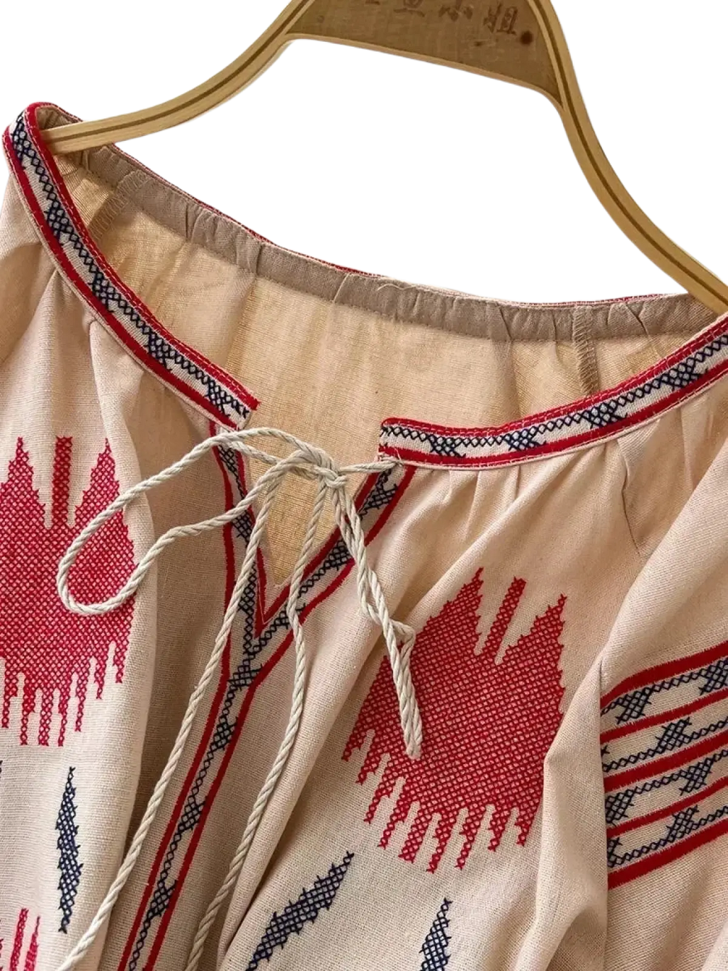 Beige embroidered boho midi dress with red and black geometric patterns and a drawstring neckline in long sleeve