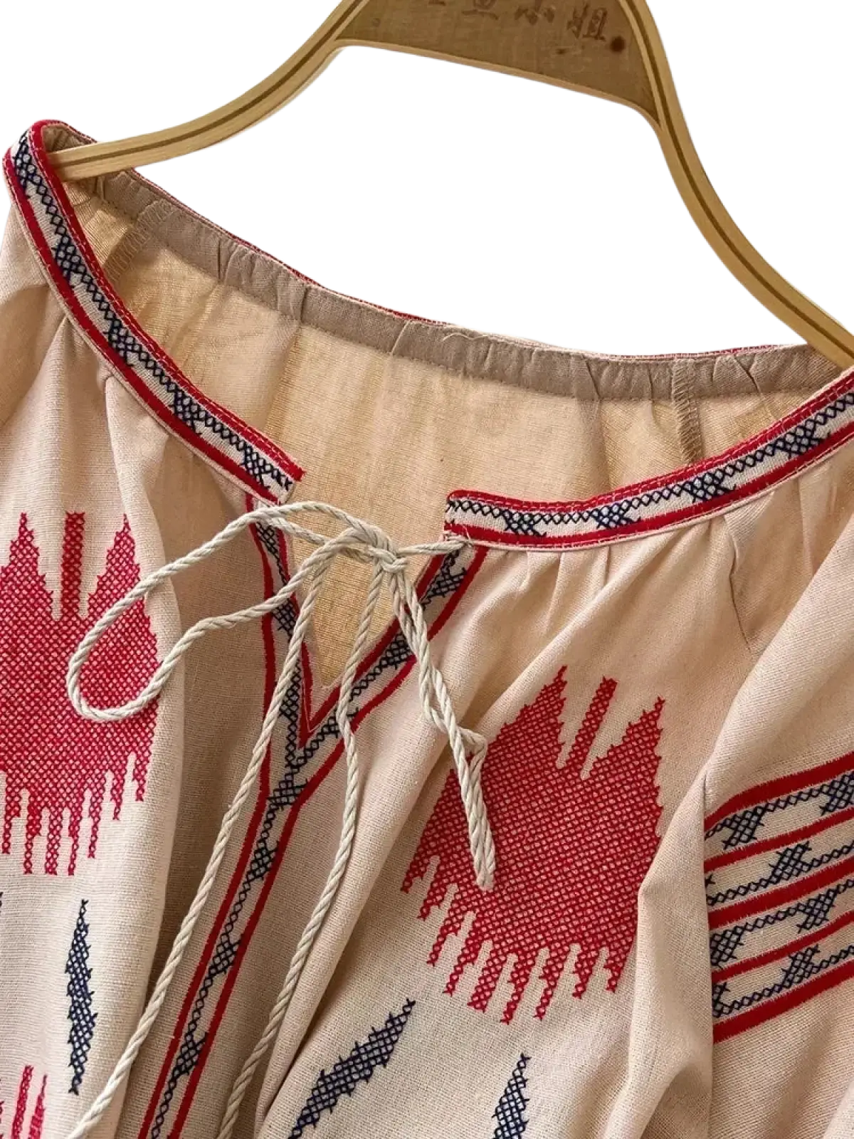 Beige embroidered boho midi dress with red and black geometric patterns and a drawstring neckline in long sleeve