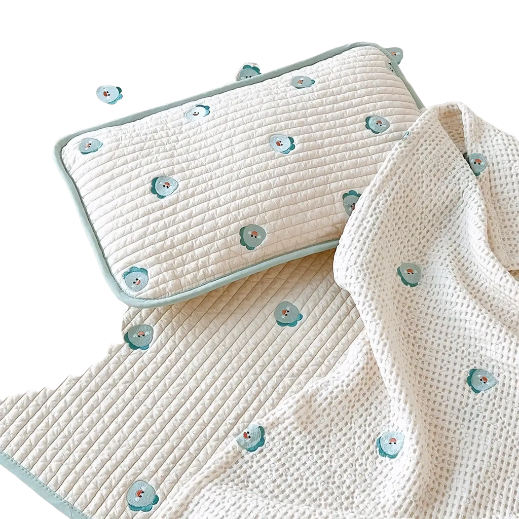 Cream-colored quilted cotton baby mat with light blue embroidered bear motifs and matching embroidered cotton baby pillow