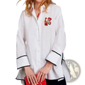 White oversized cotton blouse with black trim on cuffs and hem featuring colorful embroidered logo on left chest