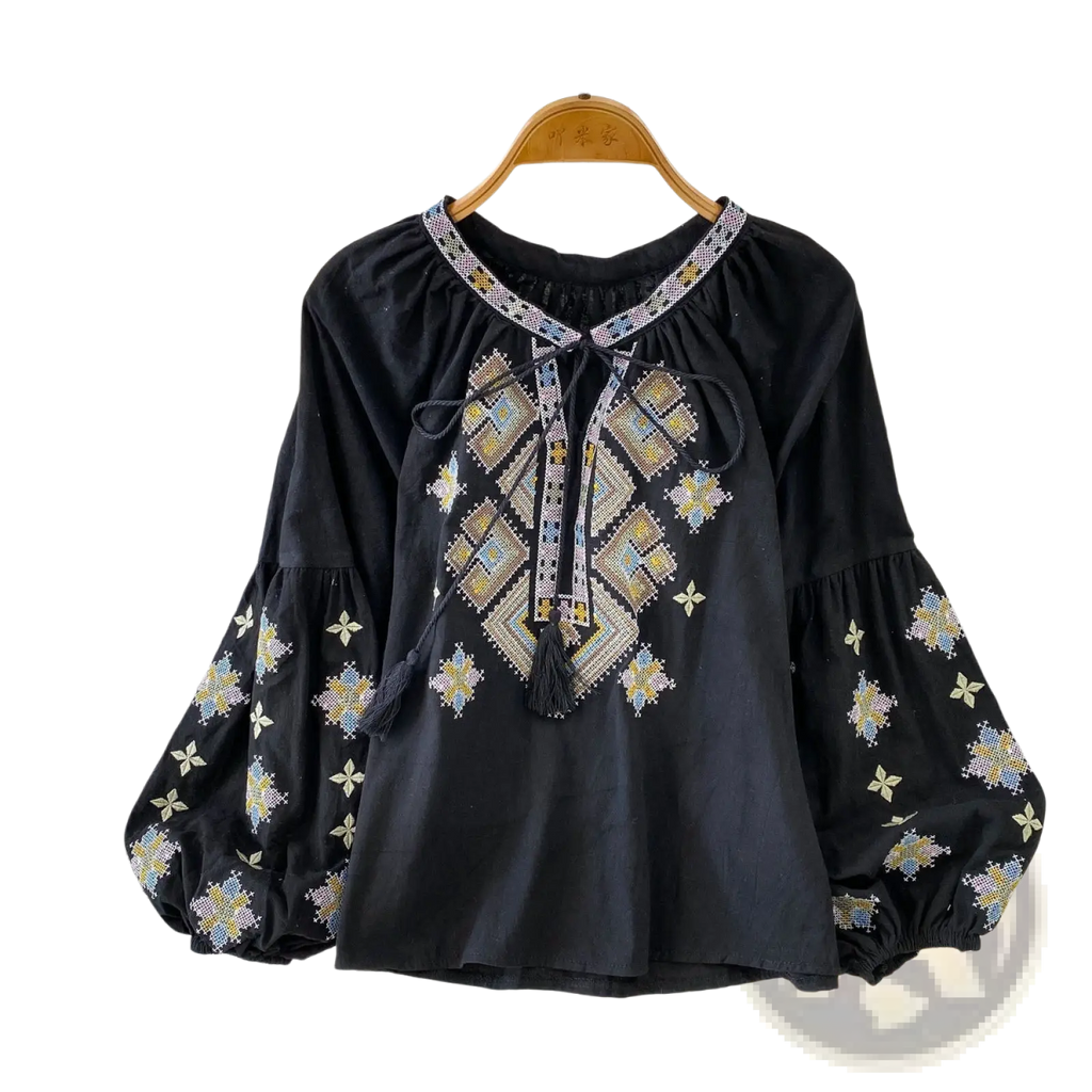 Black embroidered lantern sleeve blouse with intricate gold blue and white geometric patterns and tie front tassels