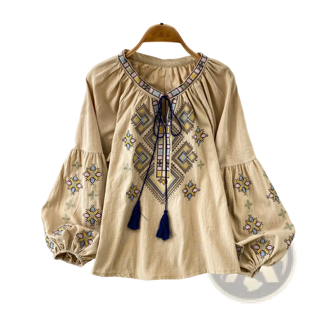 Beige embroidered lantern sleeve tie neck blouse with geometric embroidery in yellow blue and pink and navy tassels