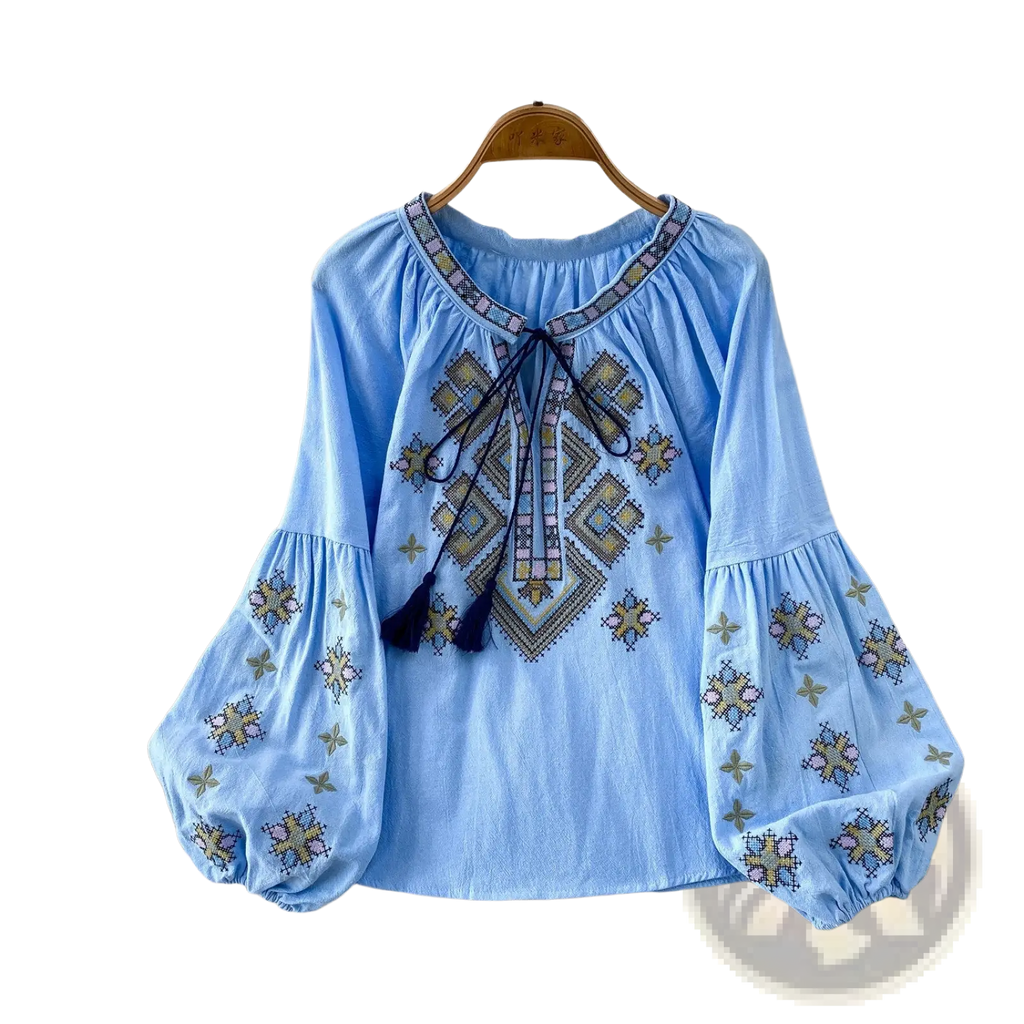 Light blue embroidered lantern sleeve blouse with geometric gold pink navy thread patterns and tie front detail