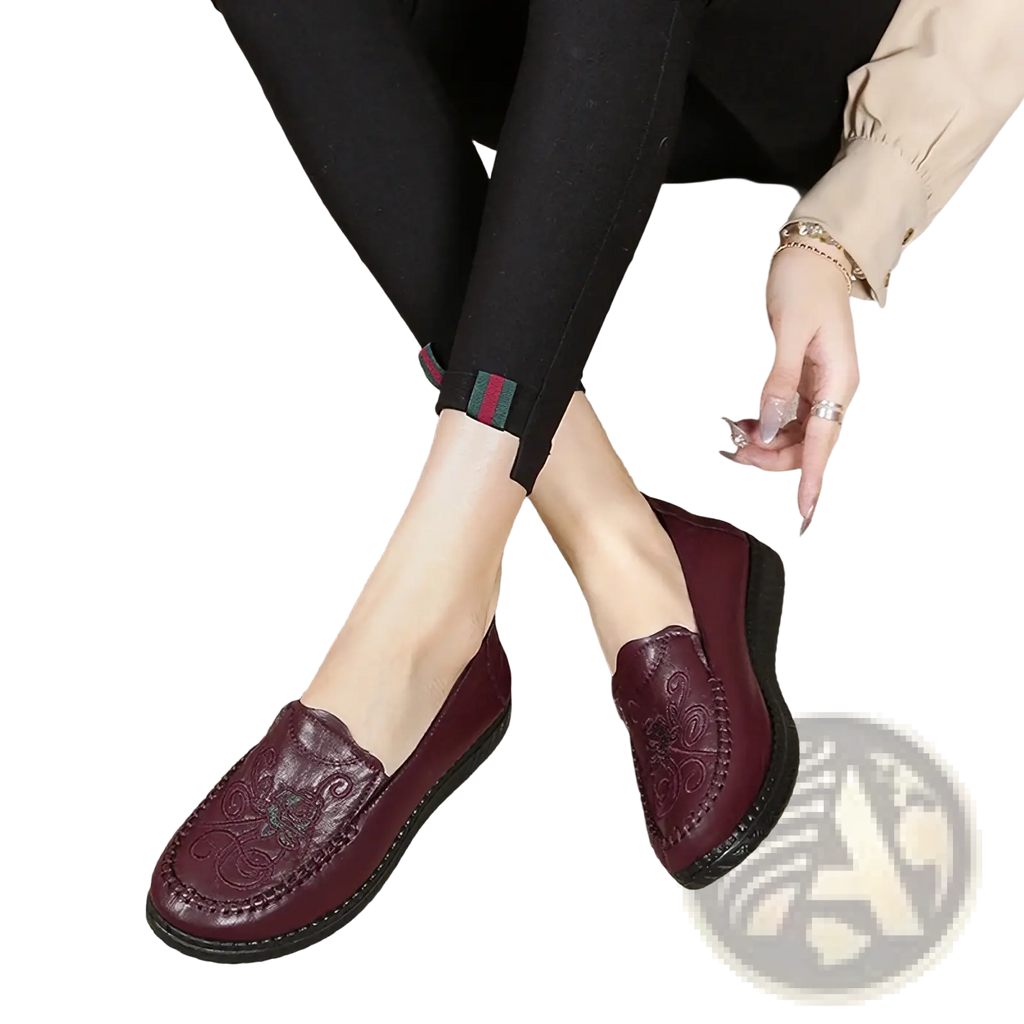 Maroon leather slip on loafers with embossed floral patterns and a black rubber sole for elegant wear
