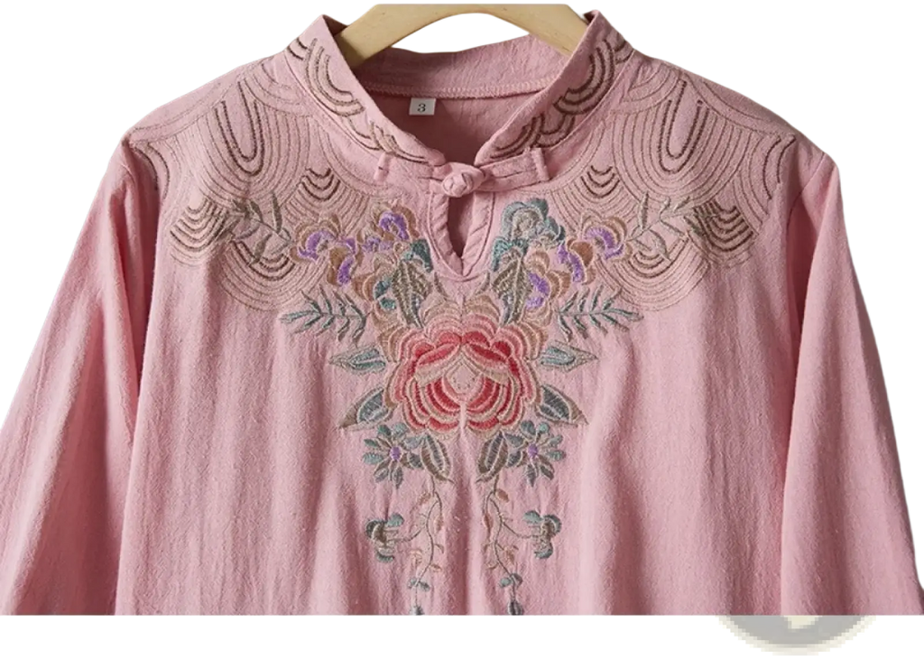 A delicate pink linen blouse with intricate floral embroidery around mandarin collar for summer outfit