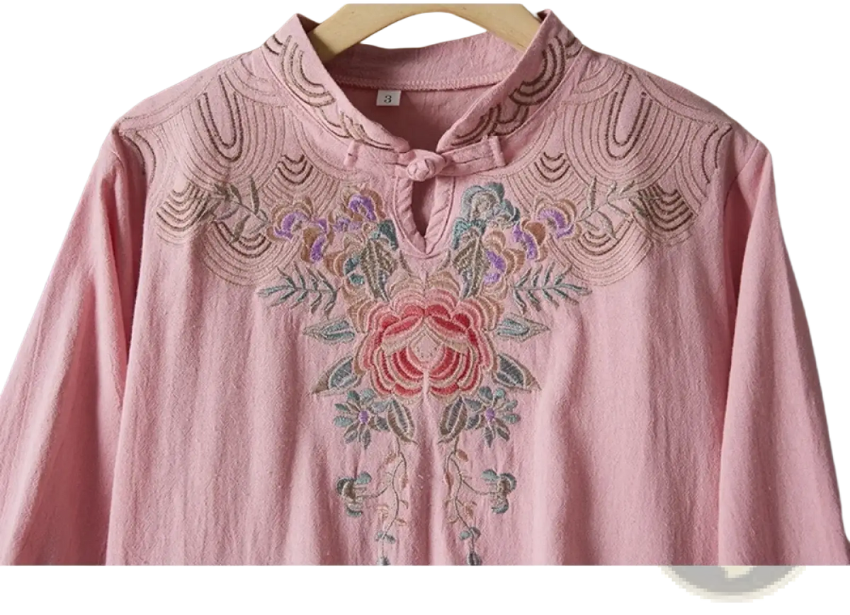 A delicate pink linen blouse with intricate floral embroidery around mandarin collar for summer outfit