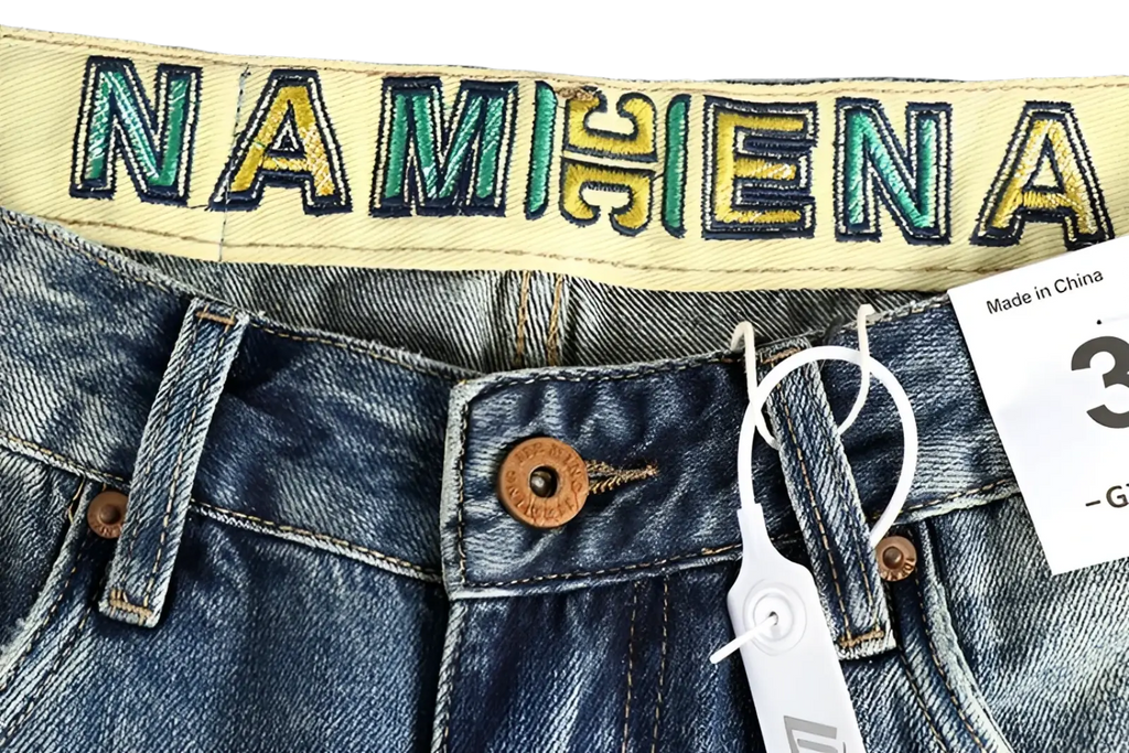 Embroidered loose fit denim jeans for men in blue with yellow waistband and green gold embroidered namihena secured by brown buttons