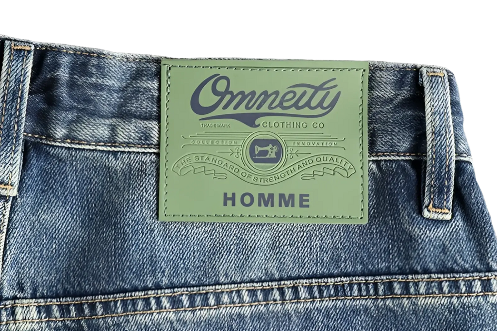 Light green leather patch with embossed branding and stitching on blue denim embroidered loose fit jeans for men back side