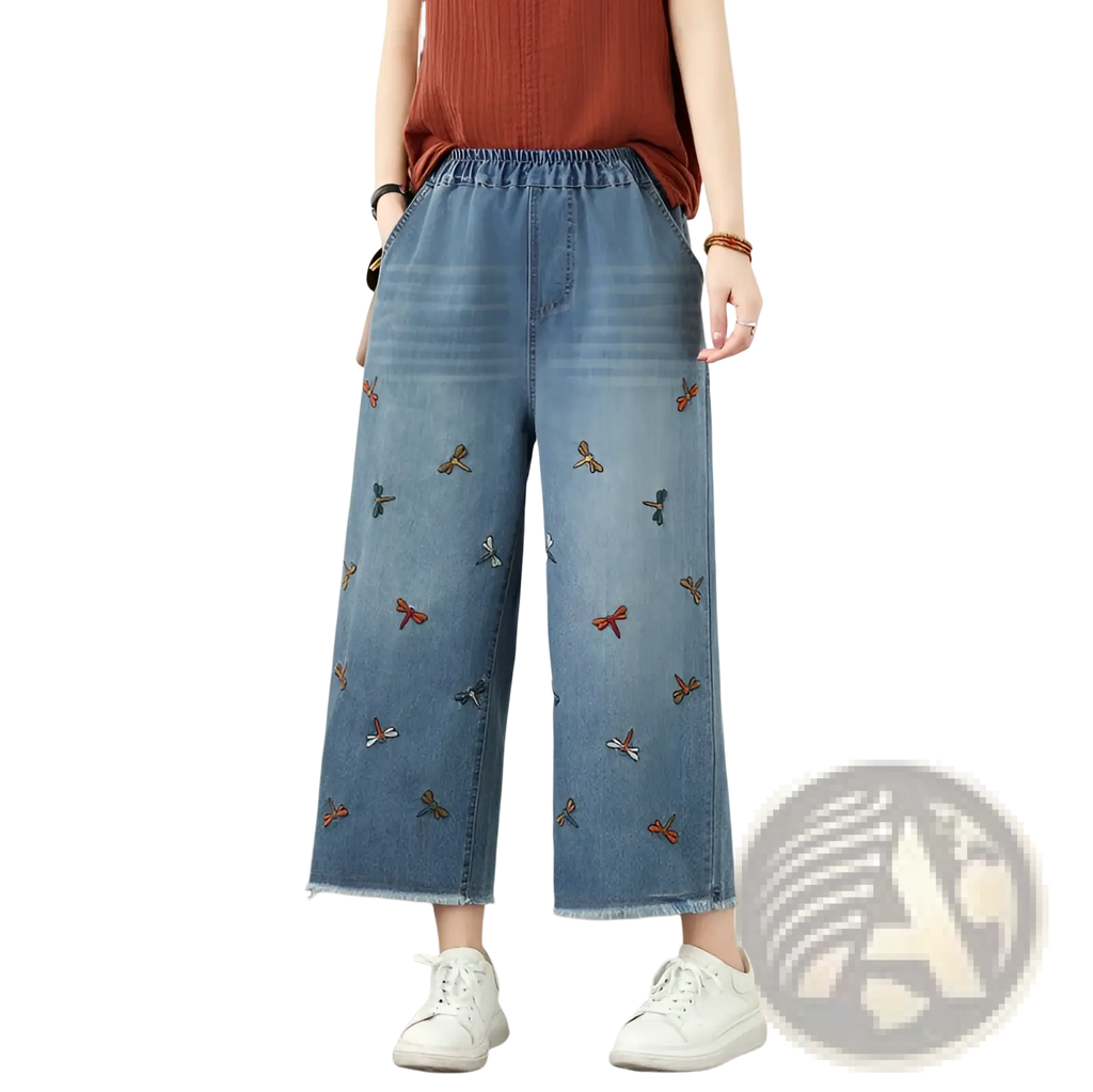 Blue denim wide leg jeans featuring colorful embroidered red orange and blue dragonflies on the front side