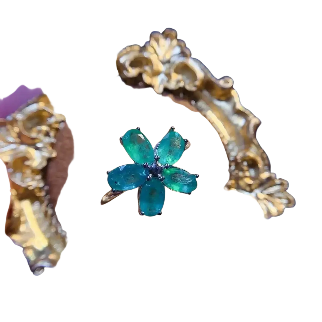 Emerald flower silver ring with five oval-cut green stones and dark blue center set in ornate gold band