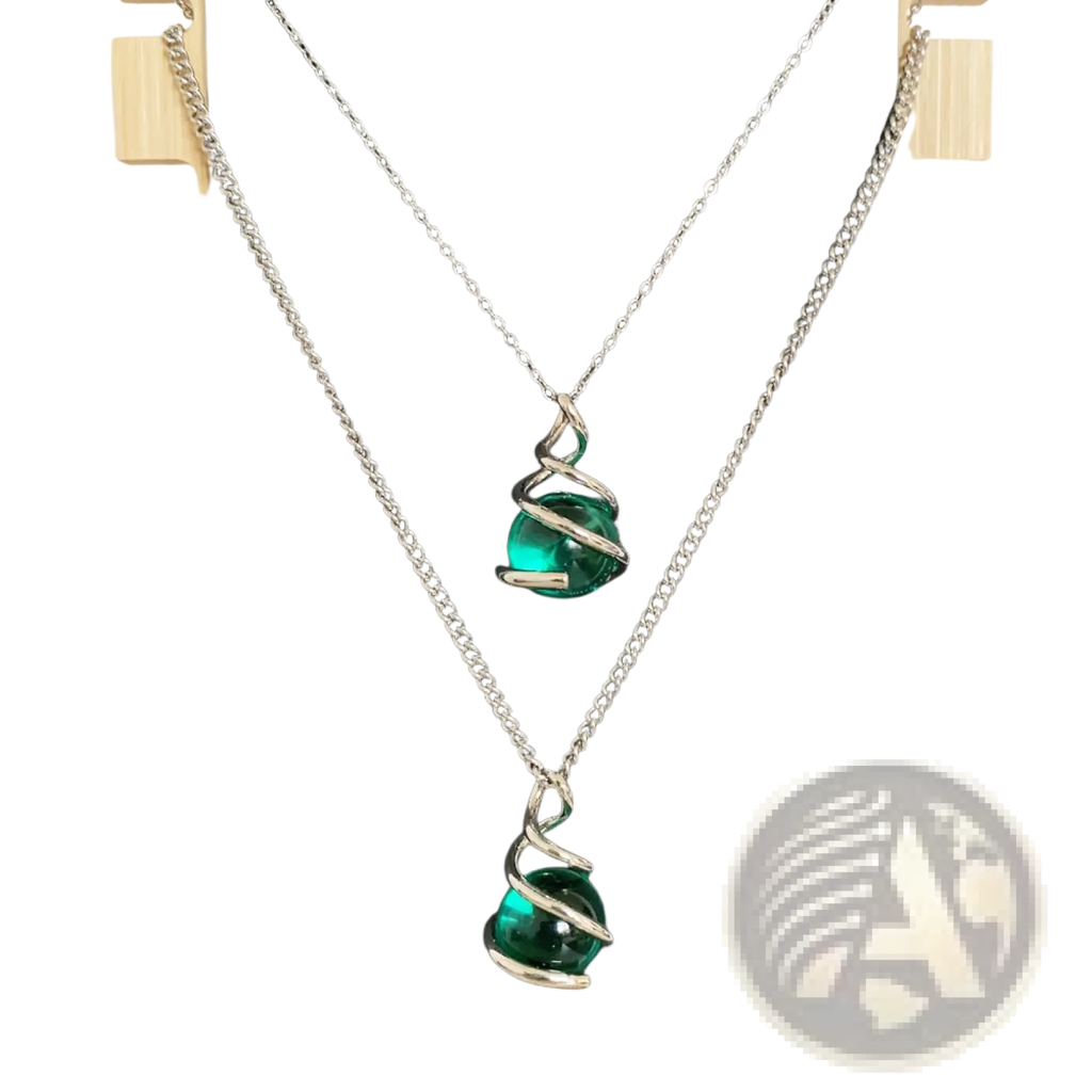 Two silver chain necklaces each with an emerald green glass sphere pendant encased in a silver spiral design