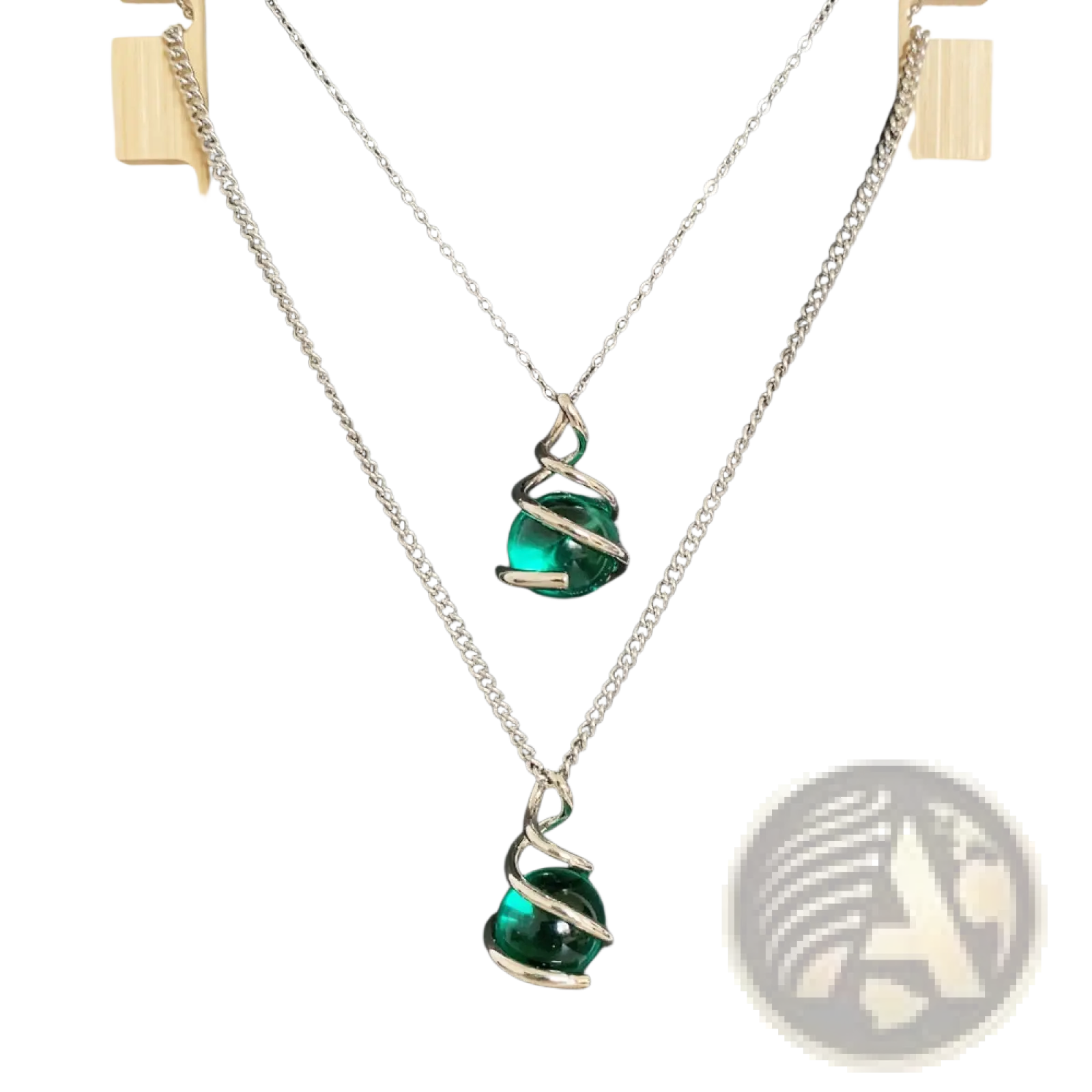 Two silver chain necklaces each with an emerald green glass sphere pendant encased in a silver spiral design
