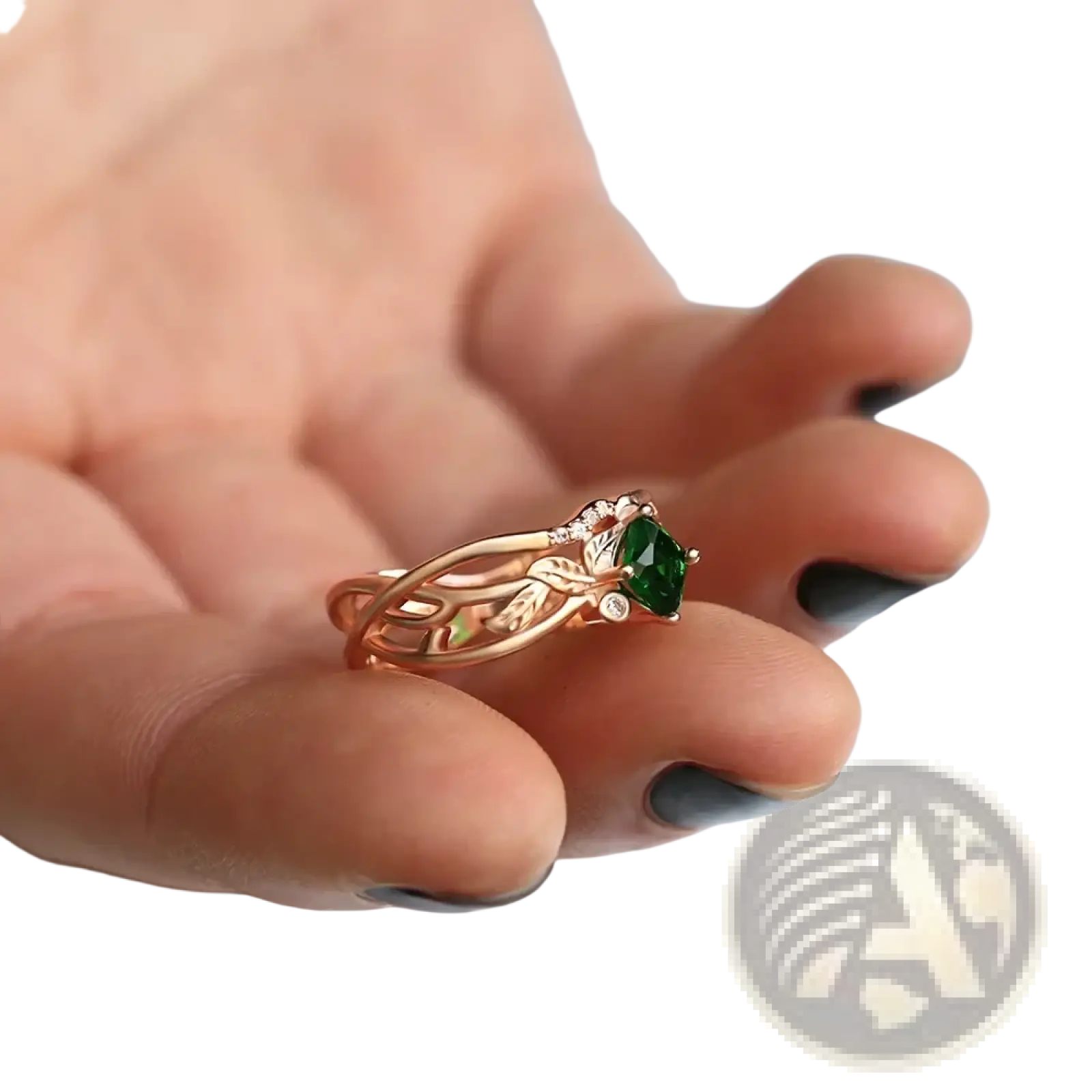 A delicate rose gold ring with a vibrant green emerald and diamond accents in an intricate leaf design