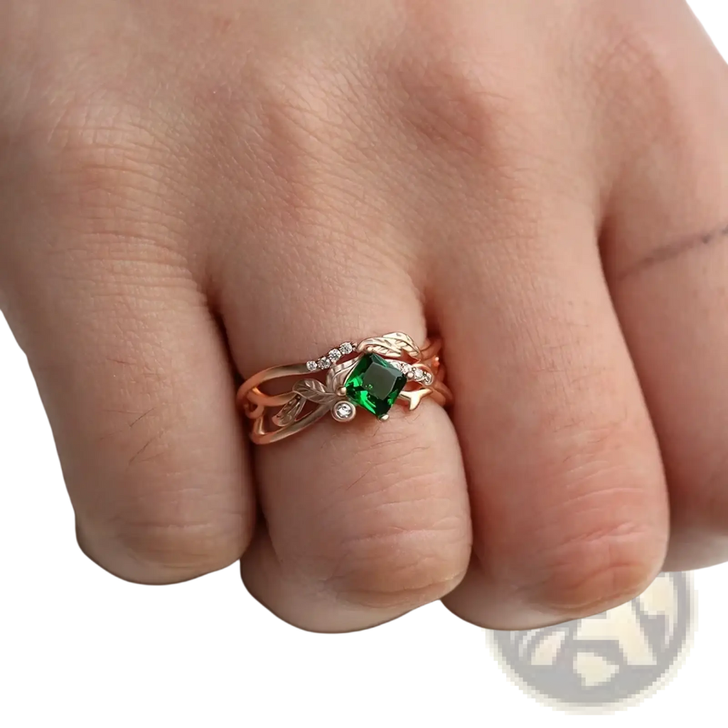 Rose gold ring with a square-cut emerald center stone and diamond leaf accents in an elegant design