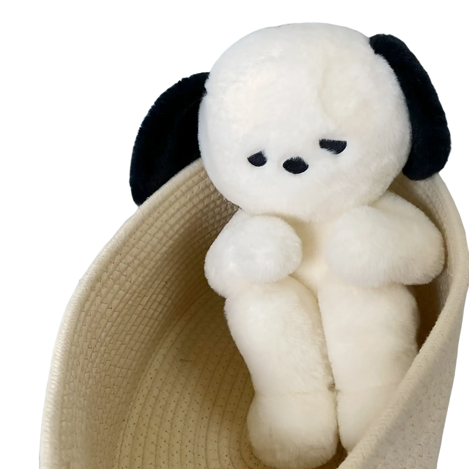 A cream-colored emo puppy plush dog with black floppy ears and embroidered face sits inside a woven basket