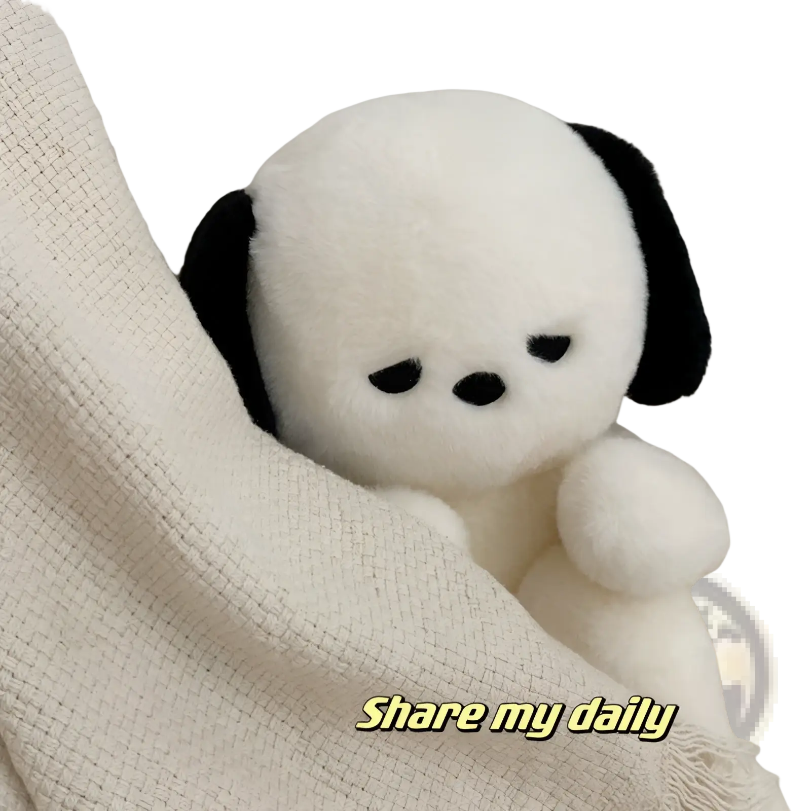 A soft white Emo puppy plush dog with black floppy ears peeks from under a textured cream-colored blanket