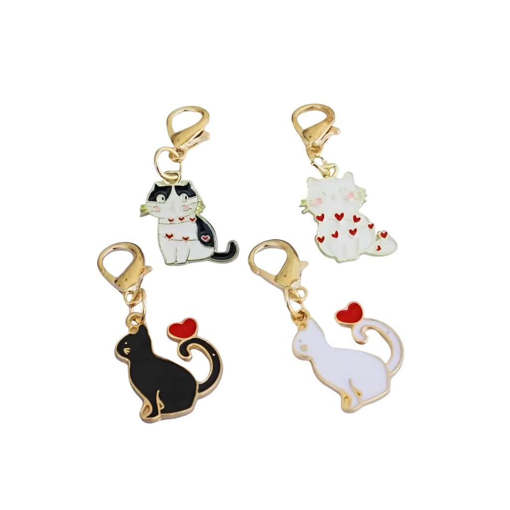 Four enamel cat keychains with gold-toned clasps in black-and-white, white with red hearts, solid black, and solid white designs