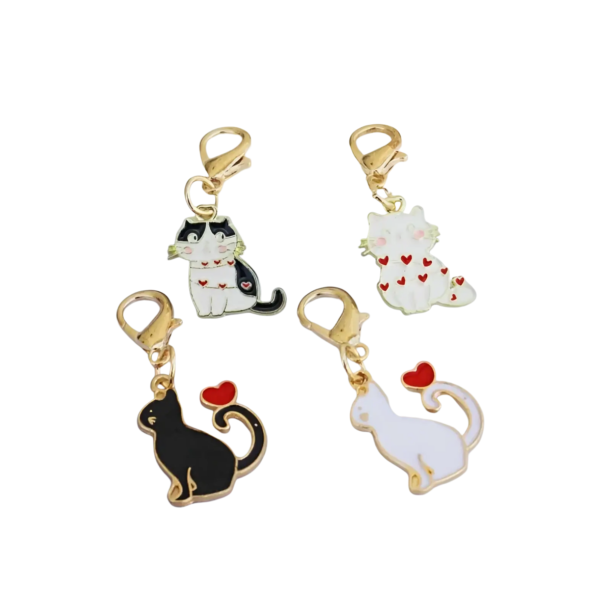 Four enamel cat keychains with gold-toned clasps in black-and-white, white with red hearts, solid black, and solid white designs