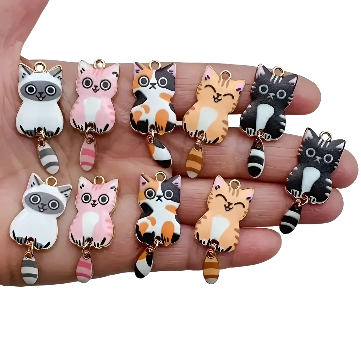 A hand holds colorful enamel cat keychain charms with gold metal loops and striped tails for cute accessories