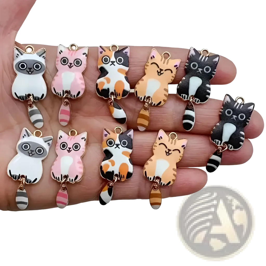 A hand holds colorful enamel cat keychain charms with gold metal loops and striped tails for cute accessories