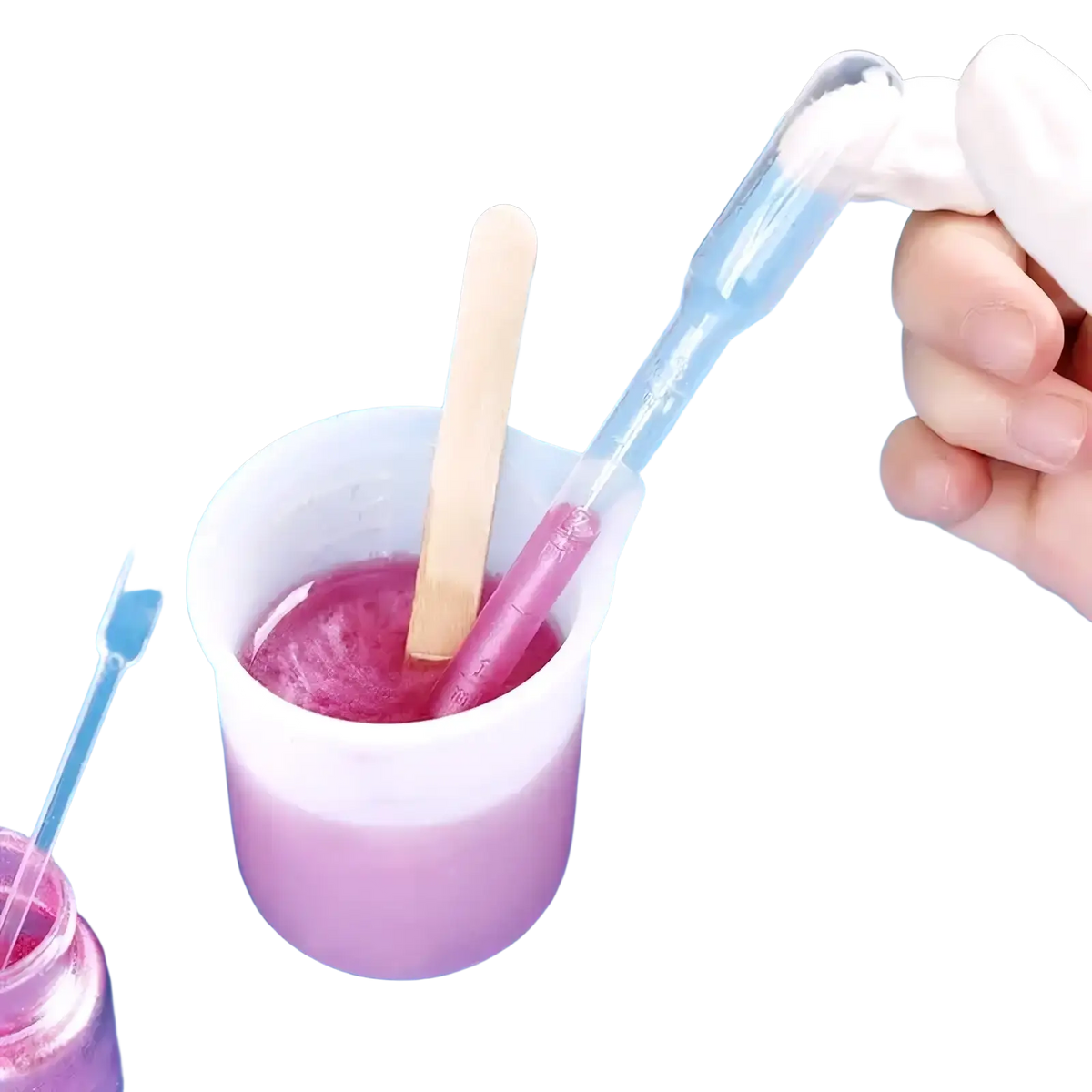 Transparent plastic pipette with white bulb transferring liquid into measuring cup with pink mixture for diy epoxy resin jewelry making