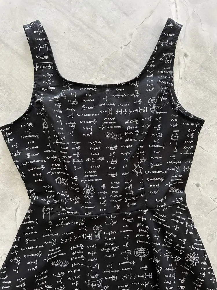 Black sleeveless skater dress with pockets featuring white equations and scientific symbols printed on fabric