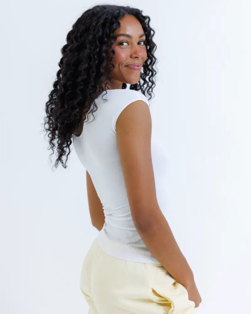 A woman wearing a white essential tri-blend scoop neck fitted tee with ribbed texture and subtle shoulder seams