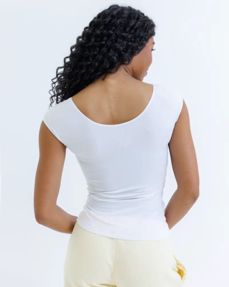 White sleeveless essential tri-blend scoop neck fitted tee with rounded neckline and slim silhouette