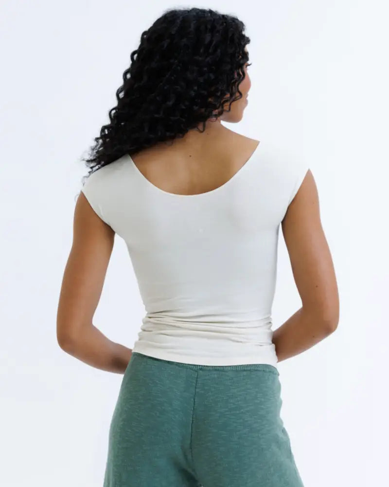 A white essential tri blend sleeveless top with a scoop neck and gathered waistband for a fitted look