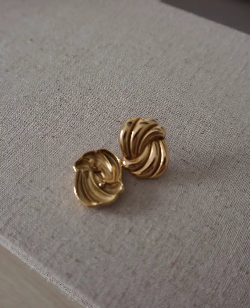Eternal gold twisted knot stud earrings in gold tone with a polished reflective finish for elegant wear
