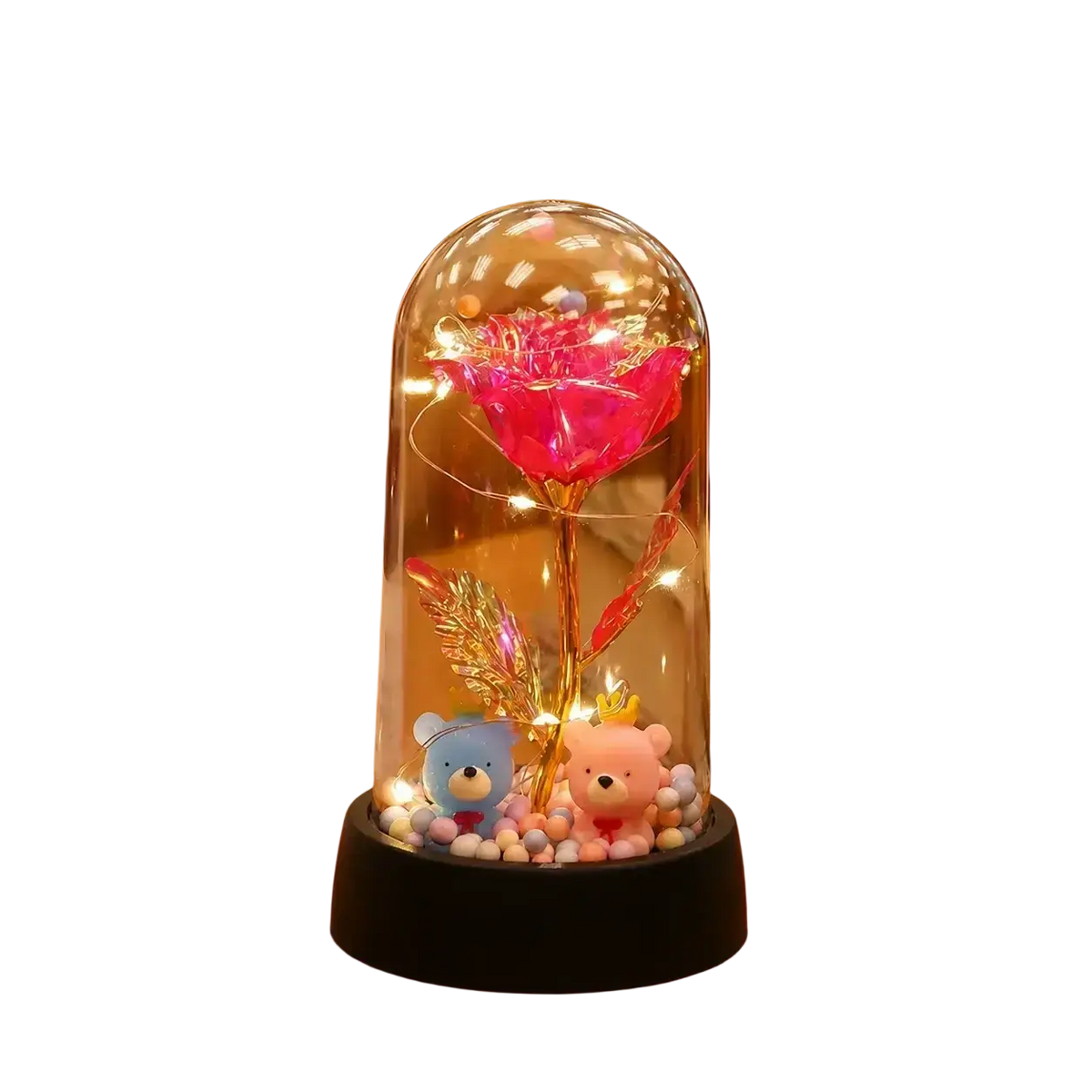 A glowing pink gold rose with a golden stem inside a glass dome illuminated by warm led light fairy lights