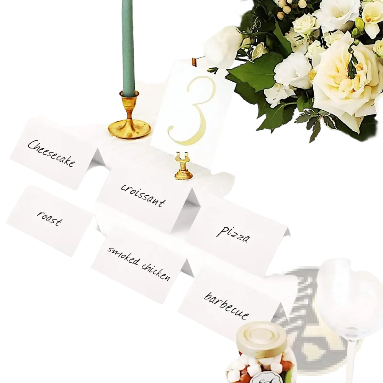 White paper eucalyptus leaf place cards with black cursive text arranged on a wedding table setting