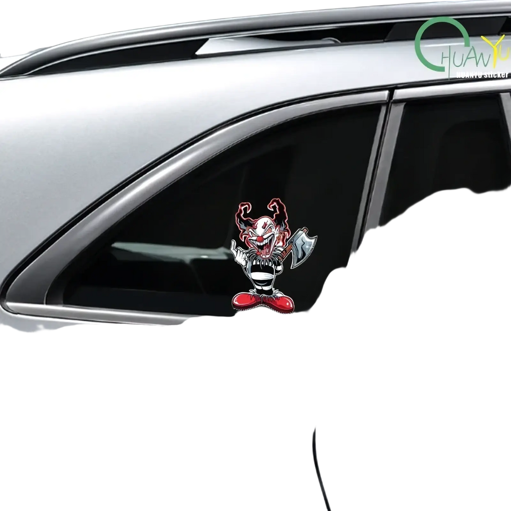 A vibrant red and black evil clown car sticker with a menacing grin and axe on the rear window of a silver car