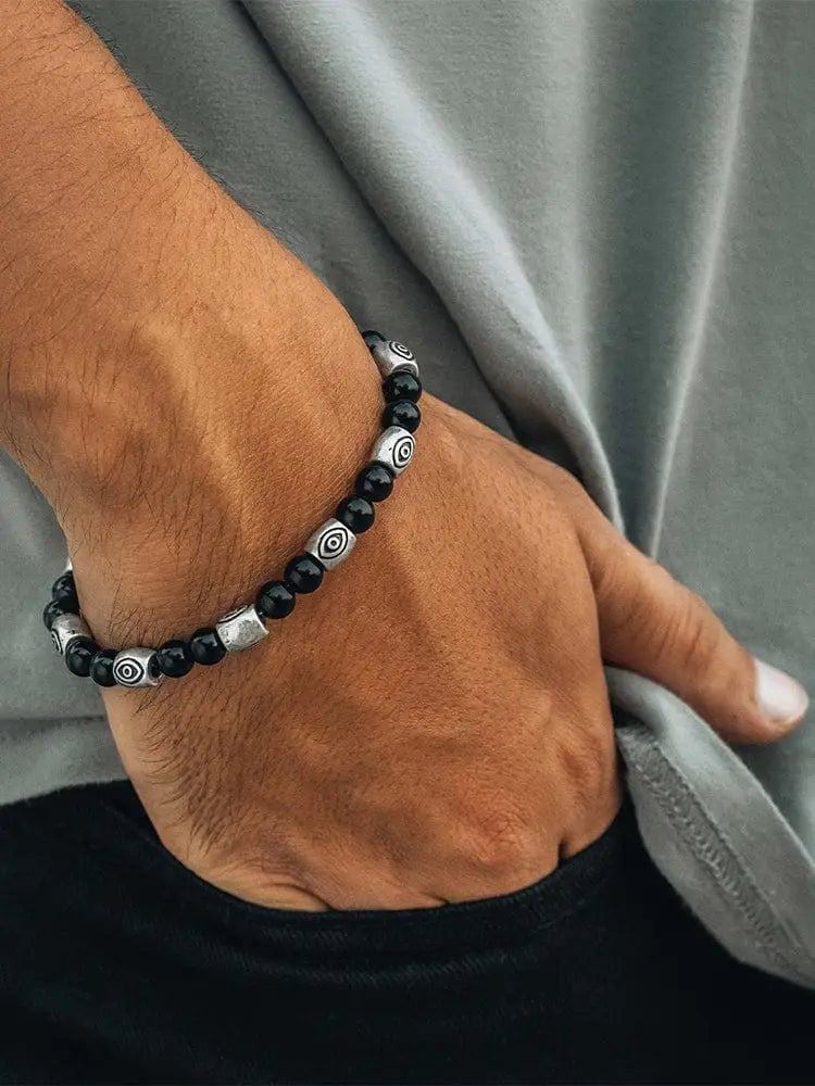 Rtzn black obsidian and silver evil eye protection bracelet with black and silver beads featuring circular engraved patterns