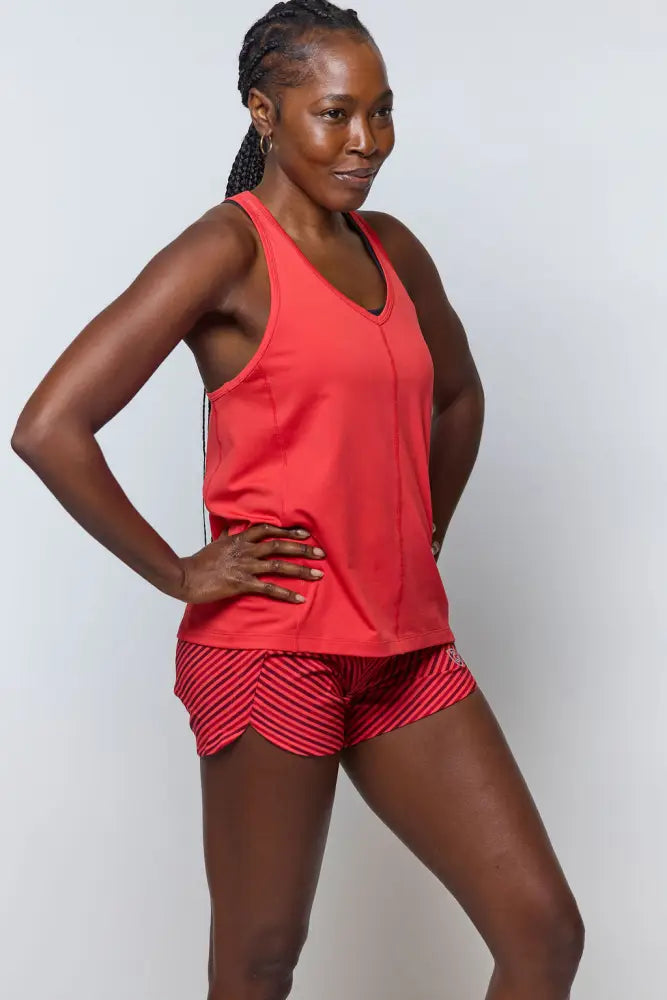 Vibrant coral sleeveless tank top with v-neckline and side seam details paired with excel women’s black camouflage athletic shorts