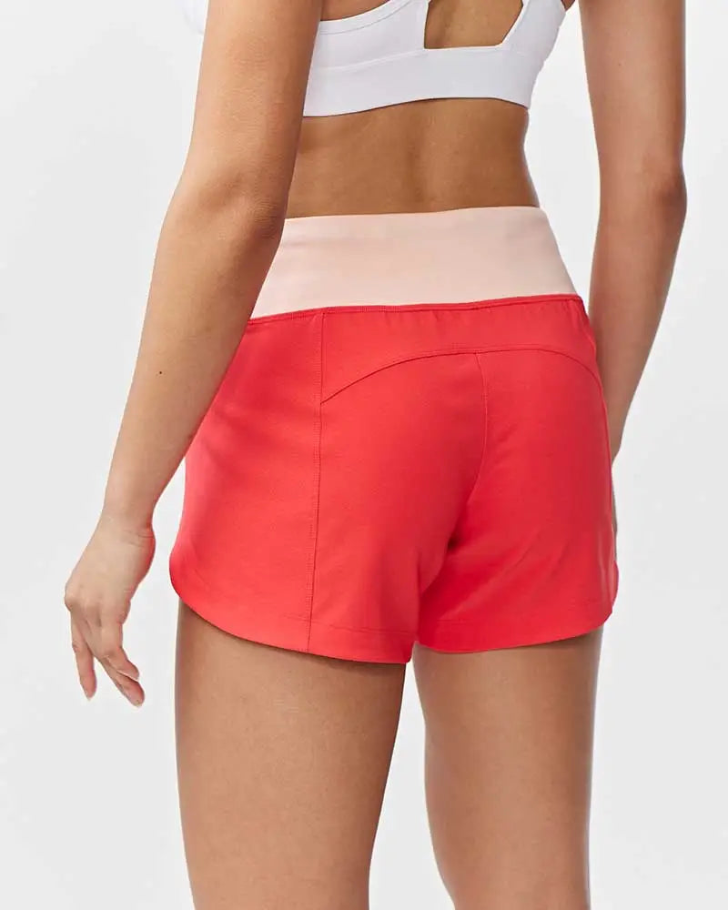 Bright coral athletic shorts with pale pink waistband complement excel women’s black camouflage workout shorts set