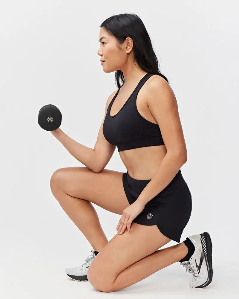 Excel women’s black camouflage athletic workout shorts shown with a black dumbbell with smooth rounded surface and logo