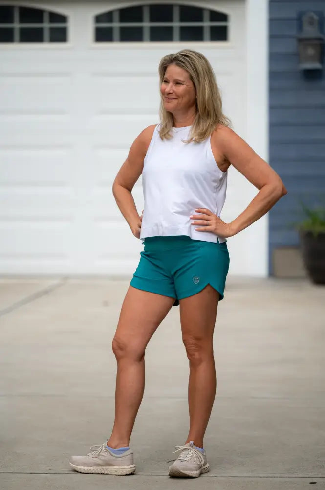 Teal women’s athletic shorts with a small logo on the left leg designed for workouts and activewear use