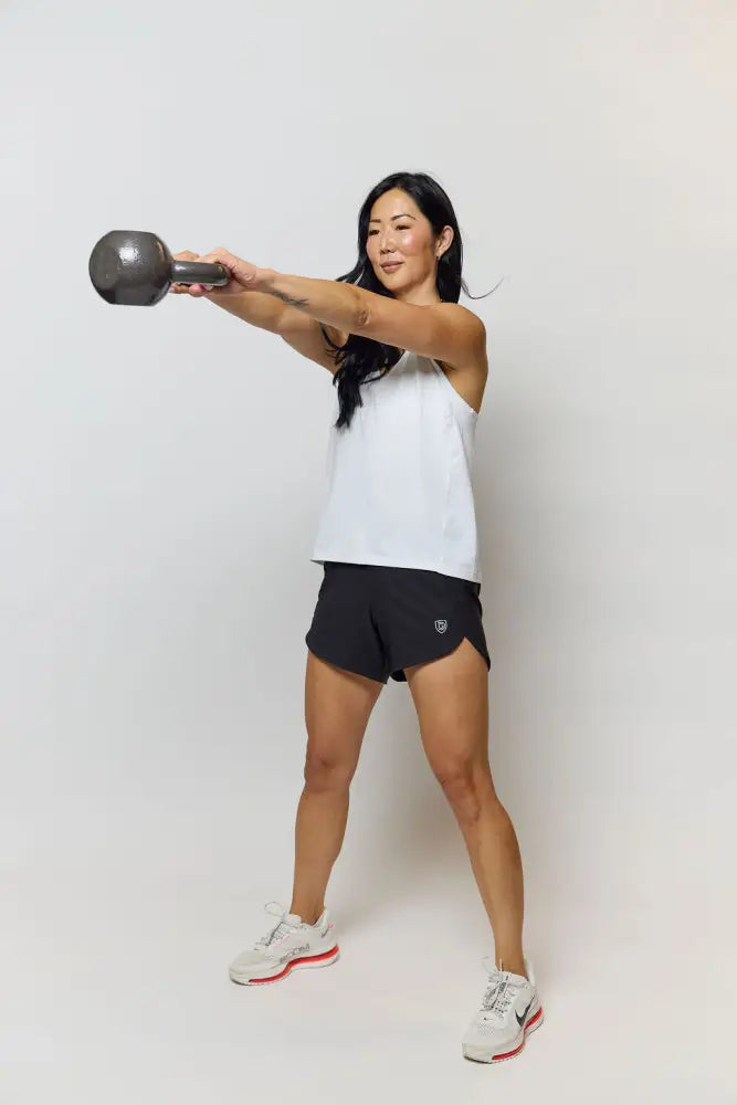 Black kettlebell with smooth rounded handle and matte finish shown alongside excel womens black camouflage workout shorts