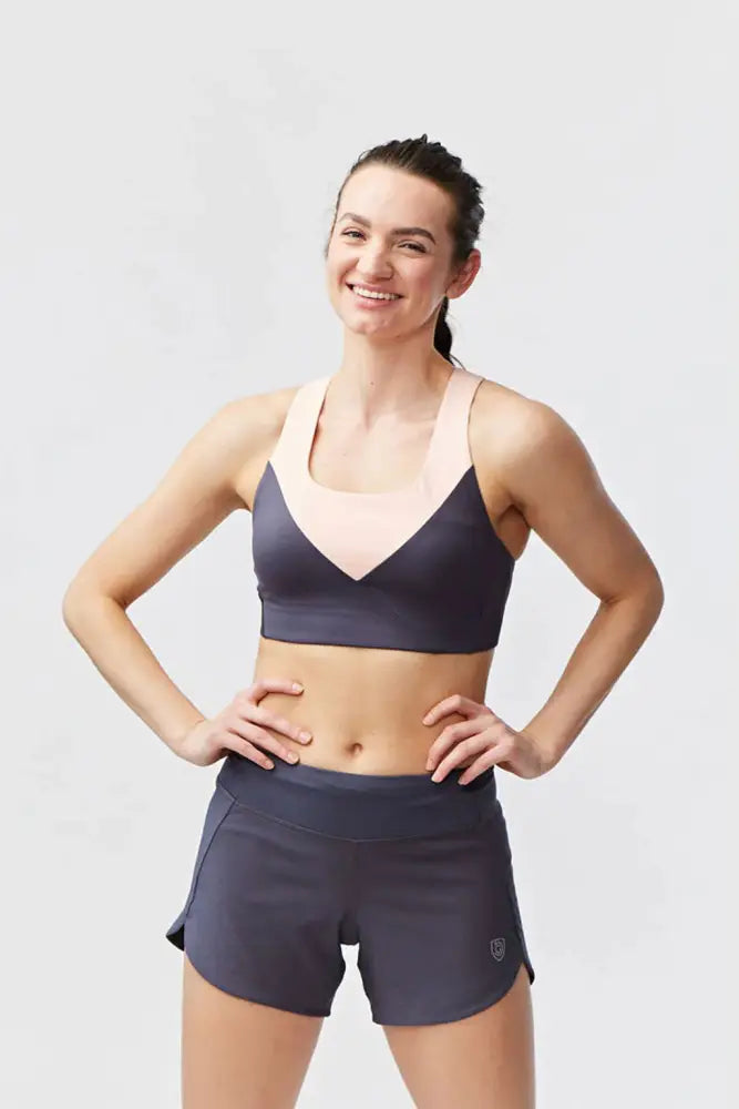 Dark gray and blush pink color-blocked sports bra with v-neckline paired with Excel Women’s black camouflage shorts
