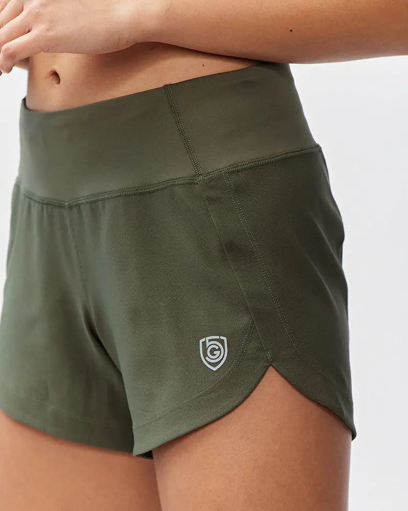 Olive green high-waisted athletic shorts with a subtle white shield logo on the side seam for workout use