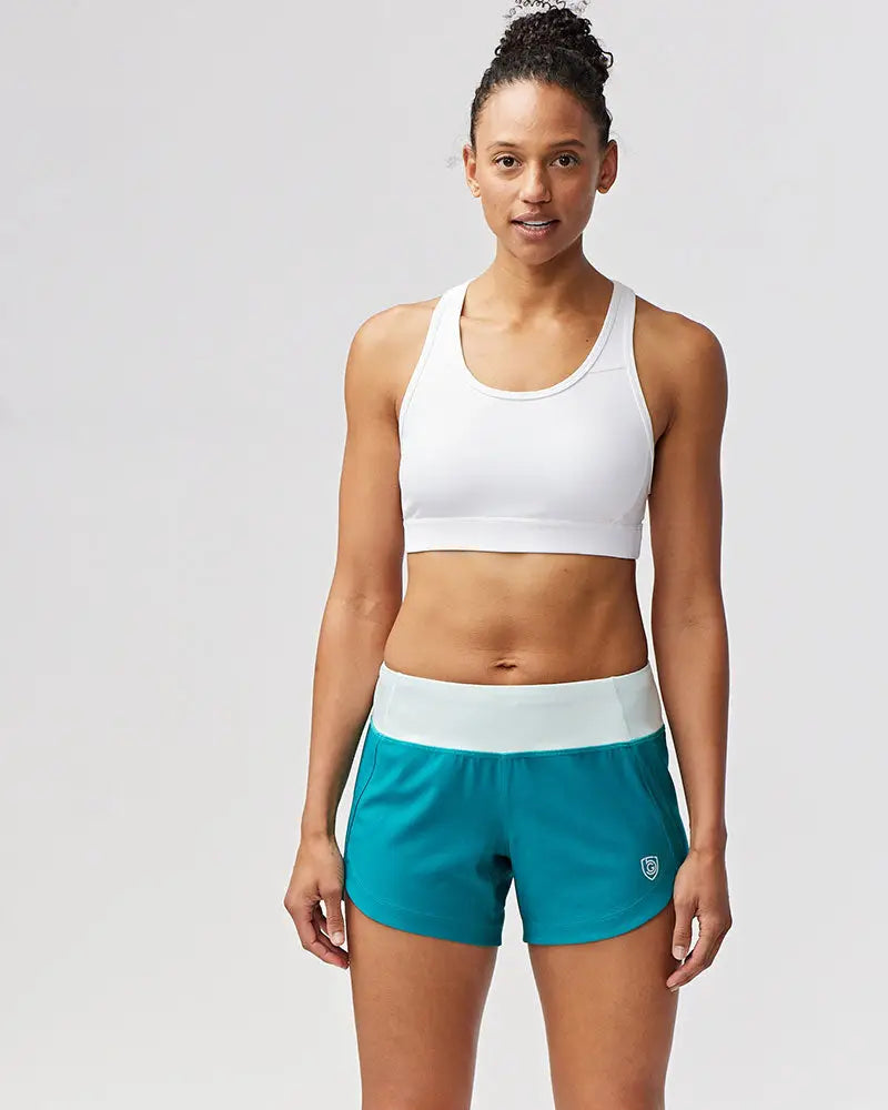 Teal excel women’s athletic shorts with white waistband and small logo on lower right leg for workout use