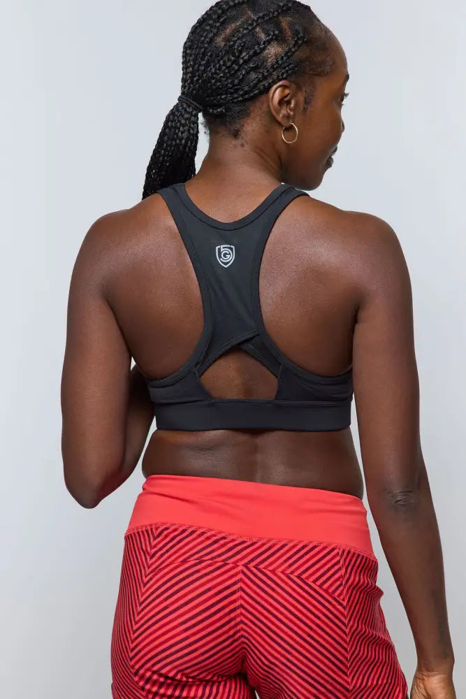 Back view of black sports bra with racerback design and white logo, paired with excel women’s black camouflage workout shorts