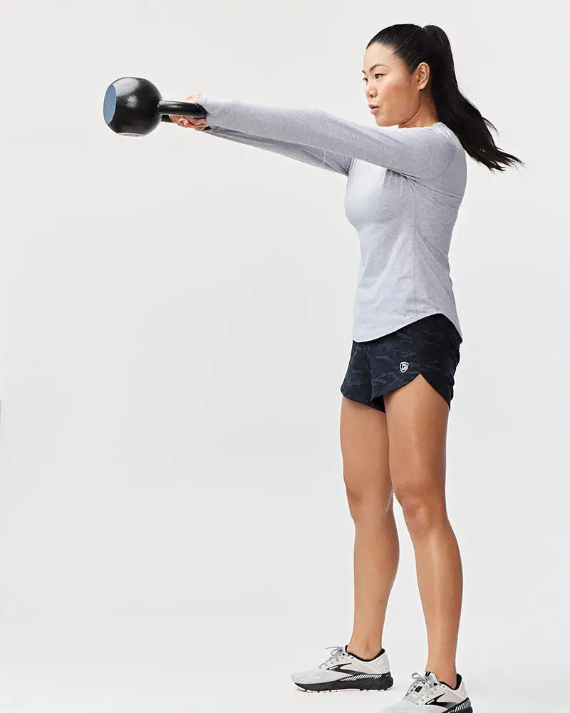 Black kettlebell with blue accent on the handle alongside Excel women’s black camouflage athletic workout shorts