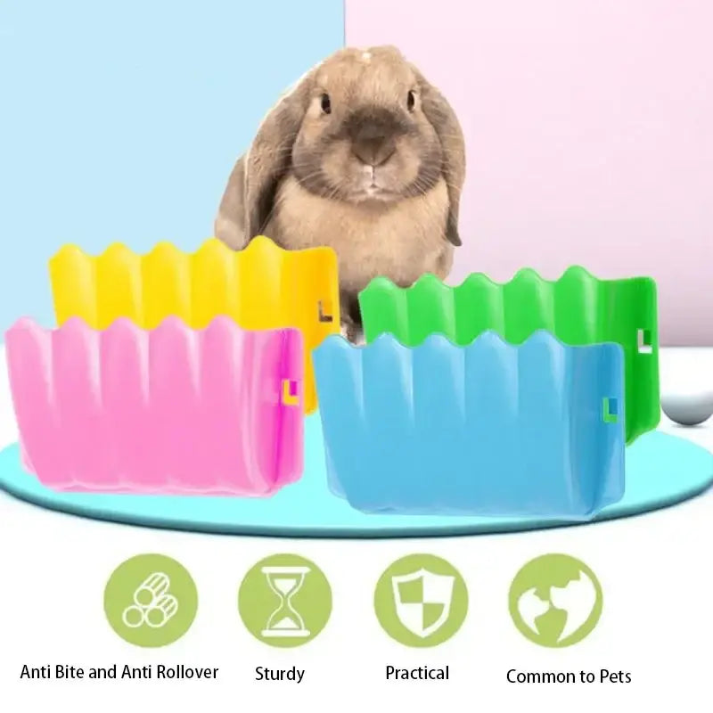 A soft light brown rabbit sits behind a colorful plastic external rabbit hay feeder food rack with pink yellow green and blue panels