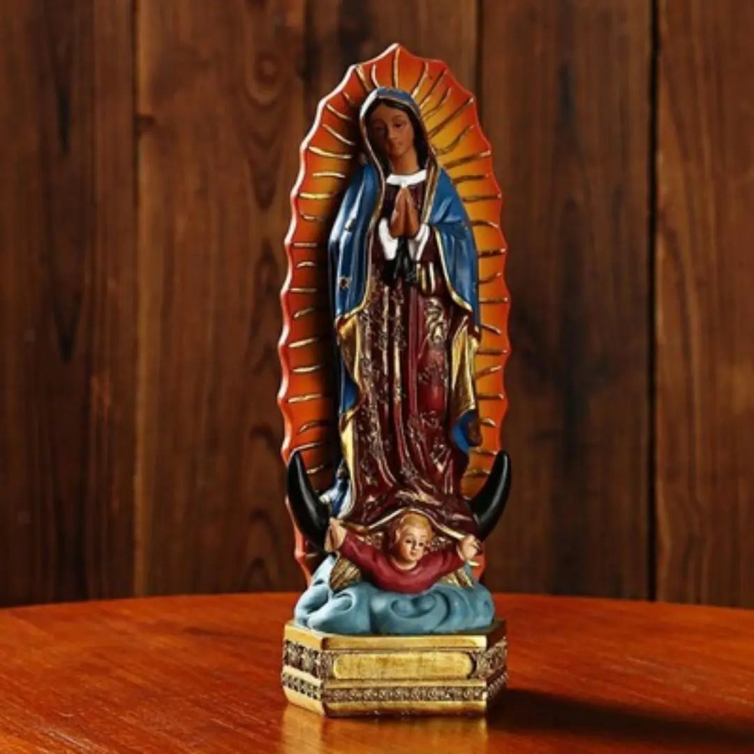 une statue en résine détaillée de 20,3 cm de Notre-Dame de Guadalupe, avec une robe bleue et dorée présentant des motifs complexes, debout sur une base dorée, sur fond de bois