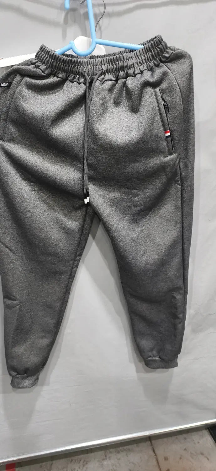 Gray fleece lined mens winter jogger pants with elastic waistband and side pockets hanging on a blue hanger