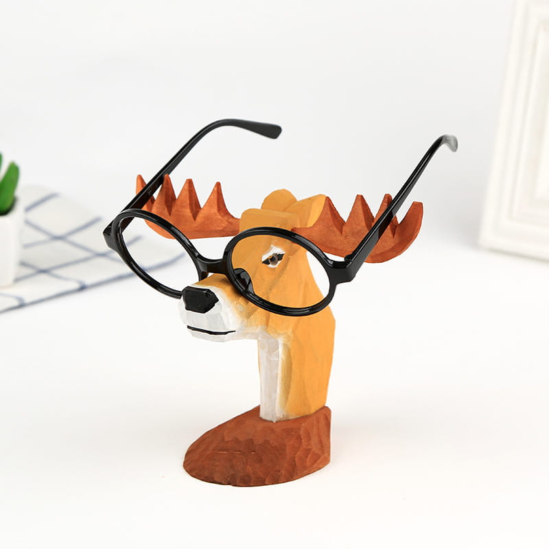 Un encantador soporte para gafas con forma de animal de madera que presenta astas naranjas y un par de gafas con montura negra apoyadas sobre su rostro, diseñado para la decoración creativa del hogar.