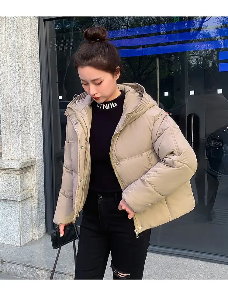 Beige women hooded short down jacket with quilted design and puffer material for cold weather.